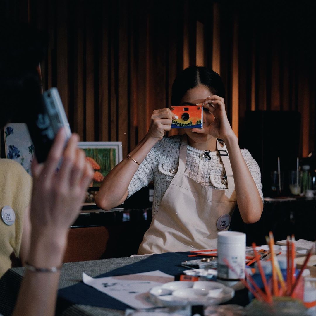 Person holding a small camera instead of a phone — analog camera revival 2026
